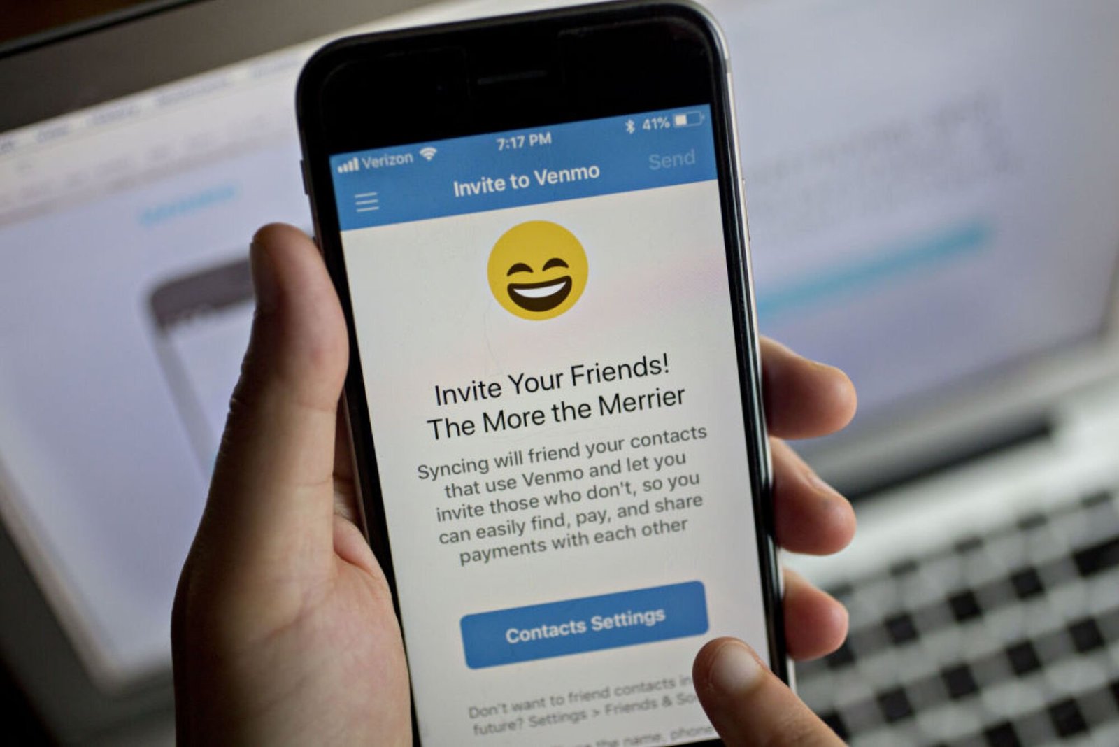 A hand holding a smartphone displaying an "Invite Your Friends" to Venmo page. 